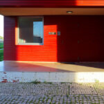 Adalberto Dias's Agra do Casto Residential Complex at the University of Aveiro showcasing a red brick and concrete façade with wooden doors and composite materials.