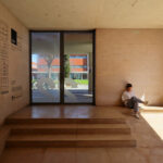 Adalberto Dias's design of the Autonomous Section of Mechanical Engineering at the University of Aveiro showcasing a modern structure with concrete and composite materials, featuring a sleek ceiling and plywood elements.
