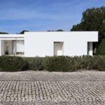 Álvaro Siza Vieira's 14 Villas at Bom Sucesso Resort showcasing a modern design with concrete walls, landscaped gardens, and a shaded estate entrance.