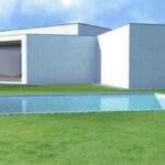 Álvaro Siza Vieira's 14 Villas at Bom Sucesso Resort showcasing a modern design with concrete structures, a swimming pool, landscaped lawn, and shaded areas within a spacious estate.
