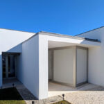 Álvaro Siza Vieira's 14 Villas at Bom Sucesso Resort showcasing modern architecture with concrete and plaster materials, featuring a minimalist design with large doors, shaded areas, and integrated landscaping.