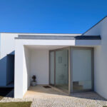 Álvaro Siza Vieira's 14 Villas at Bom Sucesso Resort showcasing a modern design with concrete walls, composite materials, and extensive daylighting, complemented by landscaping and a prominent home door.