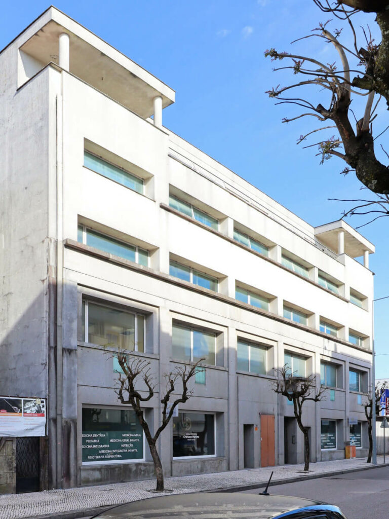 Álvaro Siza Vieira's Casa Ferreira da Costa / Casa Miranda dos Santos showcasing a minimalist design with concrete walls, aluminum-framed home doors, and a sidewalk leading to the entrance.
