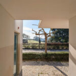 Álvaro Siza Vieira's Commercial Area at Bom Sucesso Resort showcasing a modern design with concrete walls, composite materials, and a landscaped walkway providing shade and daylighting.