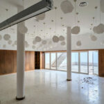 Álvaro Siza Vieira's Commercial Area at Bom Sucesso Resort showcasing a modern interior design with wooden flooring, a composite material ceiling, and contemporary lighting fixtures.