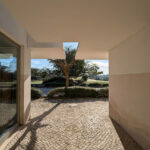 Álvaro Siza Vieira's Commercial Area at Bom Sucesso Resort showcasing a concrete structure with natural materials, integrated landscaping, and effective daylighting.
