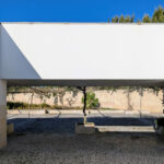 Álvaro Siza Vieira's Commercial Area at Bom Sucesso Resort showcasing a modern design with composite material, concrete structures, daylighting features, and a driveway with flagstone and tile elements.