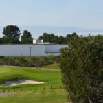 Álvaro Siza Vieira's Nave Lagoa - Event Space at Bom Sucesso Resort showcasing a sleek, modern design with a grass-covered landscape surrounding the structure, adjacent to a golf course.