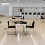 Álvaro Siza Vieira's Nave Lagoa at Bom Sucesso Resort showcasing a modern interior with sleek furniture, glass elements, and a spacious hall featuring a kitchen and dining room table.