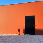 Carrilho da Graça's 14 Houses at Quinta do Bom Sucesso Resort showcasing a modern design with orange composite material walls, concrete elements, and plaster finishes casting distinct shadows.