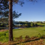 Donald Steel's Bom Sucesso Resort Golf Course showcasing expansive grasslands, meticulously maintained fairways, and a scenic reservoir within the sports venue.
