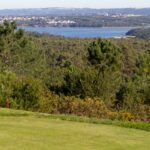 Donald Steel's Bom Sucesso Resort Golf Course showcasing expansive grasslands, a well-maintained golf course layout, and a serene reservoir backdrop.
