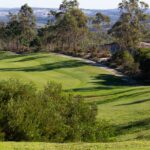 Donald Steel's design of the Bom Sucesso Resort Golf Course showcasing expansive grasslands and meticulously maintained fairways set against a backdrop of lush meadows and sports venues.