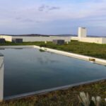Eduardo Souto de Moura's 13 C-Shaped Villas at Bom Sucesso Resort showcasing urban design with daylighting, a landscaped lawn, artificial turf, a swimming pool, and a shadowed backyard.