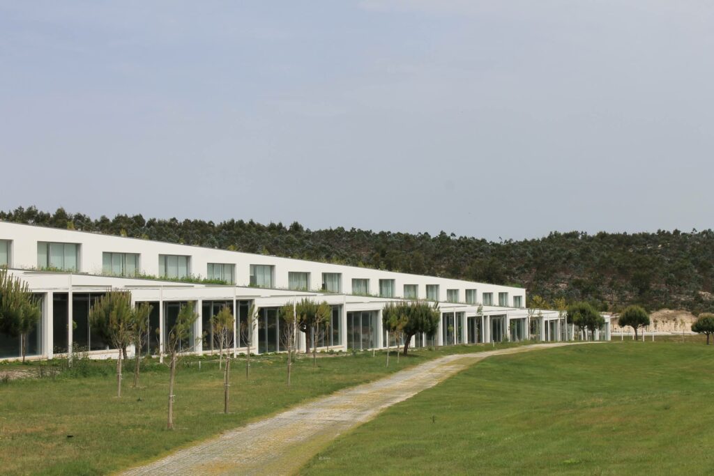 Falcão de Campos's 23 Row Houses at Bom Sucesso Resort showcasing a modern interior with wooden flooring, a spacious dining area with a kitchen and dining room table, and contemporary furniture.