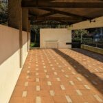 Fernando Távora's Tennis Pavilion of Quinta da Conceição showcasing a minimalist design with a wooden structure, concrete flooring, and brown composite materials.