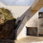 Gonçalo Byrne's Urban Requalification of São Martinho do Porto showcasing a modern architectural design with concrete stairs, composite material walls, and a handrail, emphasizing daylighting and slope integration.