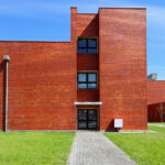 Jorge Kol de Carvalho's Department of Communication and Arts, University of Aveiro, showcasing a modern urban design with brickwork walls, composite materials, and a well-maintained lawn.
