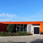 Luís Pessanha Moreira's 27 Row Houses at Bom Sucesso Resort showcasing a vibrant red and orange exterior with landscaped yards and hacienda-style design elements.