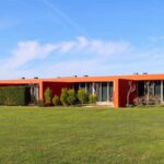 Luís Pessanha Moreira's 27 Row Houses at Bom Sucesso Resort showcasing a modern design with orange accents, a landscaped lawn, and eco-friendly features in the backyard.