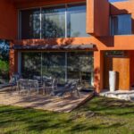 Madalena Menezes and Teixeira Bastos's 18 Row Houses at Bom Sucesso Resort showcasing a modern urban design with wood-stained balconies, landscaped yards, and shaded villa-style structures.