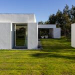 Manuel Aires Mateus's 7 Row Houses at Bom Sucesso Resort showcasing a modern design with a landscaped backyard, grass lawn, and shaded areas.