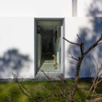 Manuel Aires Mateus's 7 Row Houses at Bom Sucesso Resort showcasing a modern design with composite material, concrete structure, grey tones, and daylighting elements, featuring plaster finishes and home doors casting shadows.