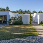 Manuel Aires Mateus's 7 Row Houses at Bom Sucesso Resort showcasing a modern design with concrete structures, landscaped gardens, and a shaded courtyard.