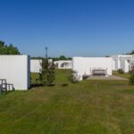 Manuel Aires Mateus's 7 Row Houses at Bom Sucesso Resort showcasing a modern design with concrete structures, landscaped gardens, and expansive grassy lawns.