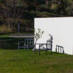 Manuel Aires Mateus's 7 Row Houses at Bom Sucesso Resort showcasing minimalist design with flat roofs, large glass windows, and surrounded by grassy meadows.