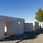 Manuel Aires Mateus's 7 Row Houses at Bom Sucesso Resort showcasing a modern design with concrete structures, composite materials, and strategic daylighting creating shadows during the daytime.