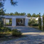 Manuel Aires Mateus's 7 Row Houses at Bom Sucesso Resort showcasing a modern design with concrete structures, landscaped gardens, and a central courtyard surrounded by evergreen shrubs and conifers.
