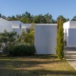 Manuel Aires Mateus's 7 Row Houses at Bom Sucesso Resort showcasing a modern design with concrete structures, integrated garden landscaping, and conifers enhancing daylighting.