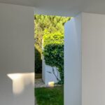 Manuel Aires Mateus's 7 Row Houses at Bom Sucesso Resort showcasing a modern design with concrete structures, extensive use of daylighting, and landscaped gardens with hedges and evergreen plants.