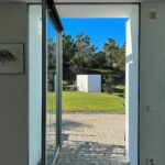 Manuel Aires Mateus's 7 Row Houses at Bom Sucesso Resort showcasing a modern design with concrete and composite materials, featuring large glass sliding doors, aluminum elements, and integrated landscaping for daylighting.
