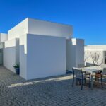 Manuel Aires Mateus's 7 Row Houses at Bom Sucesso Resort showcasing a modern urban design with concrete and plaster materials, featuring daylighting elements and shaded areas.