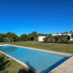 Manuel Aires Mateus's 7 Row Houses at Bom Sucesso Resort showcasing a modern design with a blue swimming pool, composite materials, and a reflecting pool integrated into the landscaped resort setting.