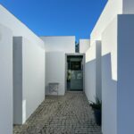 Manuel Aires Mateus's 7 Row Houses at Bom Sucesso Resort showcasing a modern urban design with grey concrete and plaster materials, featuring daylighting and tile elements.