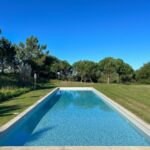 Manuel Aires Mateus's 7 Row Houses at Bom Sucesso Resort showcasing a modern design with composite materials, a blue swimming pool, landscaped garden, and shaded backyard in a tropical setting.
