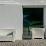 Manuel Aires Mateus's 7 Row Houses at Bom Sucesso Resort showcasing a minimalist design with white and grey concrete structures, outdoor furniture, and shaded areas.
