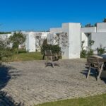 Manuel Aires Mateus's 7 Row Houses at Bom Sucesso Resort showcasing a modern design with concrete structures, landscaped courtyards, and shaded garden areas.