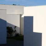 Manuel Aires Mateus's 7 Row Houses at Bom Sucesso Resort showcasing a modern urban design with concrete and composite materials, featuring shaded areas and daylighting elements integrated into the landscaping.
