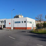 Maria Emília Pedroso Lima's design of the Higher Institute of Accounting and Administration, University of Aveiro, showcasing urban design elements with a street light, asphalt road surface, and sidewalk in the public space.