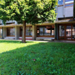 Noémia de Azevedo Coutinho's Conservatório de Música de Aveiro Calouste Gulbenkian showcasing a landscaped courtyard with palm trees, a shaded lawn, and a driveway leading to the main entrance.