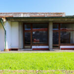 Noémia de Azevedo Coutinho's Conservatório de Música de Aveiro Calouste Gulbenkian showcasing a modern design with a concrete structure, expansive lawn, and wood-stained elements providing shade and daylighting in the yard.