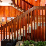 Noémia de Azevedo Coutinho's Conservatório de Música de Aveiro Calouste Gulbenkian showcasing an interior with wooden stairs, brown hardwood finishes, and a sleek handrail design.