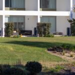 Nuno Graça Moura's 24 Row Houses at Bom Sucesso Resort showcasing a modern villa design with a landscaped garden, shaded lawn, and neatly trimmed hedges.