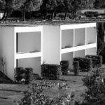 Nuno Graça Moura's 24 Row Houses at Bom Sucesso Resort showcasing a modern design with a landscaped garden, neatly trimmed hedges, and integrated green spaces.