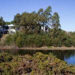 Nuno Graça Moura's 24 Row Houses at Bom Sucesso Resort showcasing a modern design with a natural landscape backdrop, featuring water resources and lush vegetation.