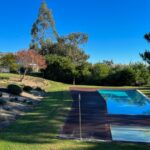 Nuno Graça Moura's 24 Row Houses at Bom Sucesso Resort showcasing a modern design with a blue swimming pool, lush landscaping, and a well-maintained lawn in the backyard.